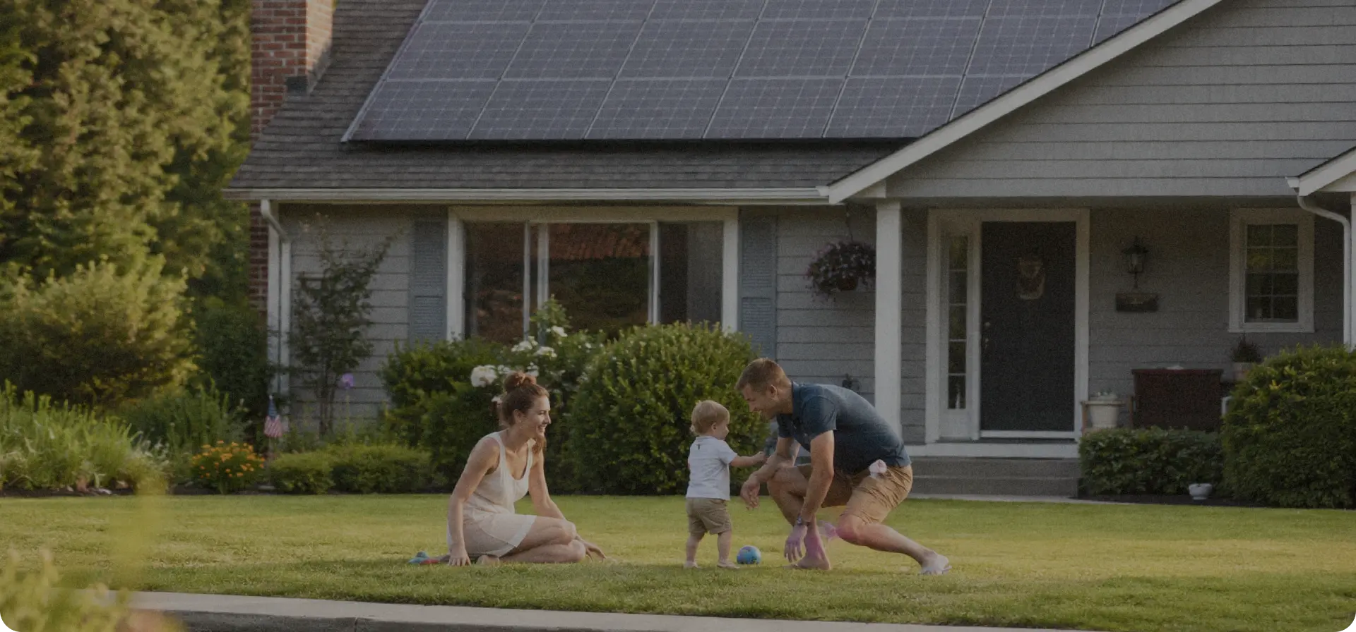 Family playing on the lawn in front of a home with rooftop solar panels
